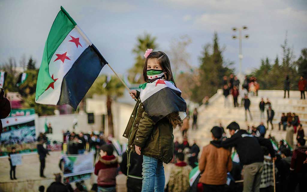 girl holding Syrian flag at rally